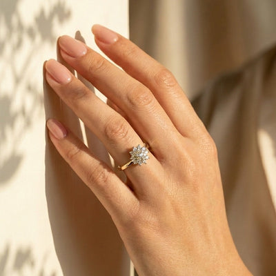 Hand wearing a diamond ring with a neutral background
