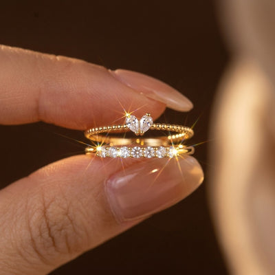 Close-up of a hand wearing multiple gold and diamond rings on a dark background