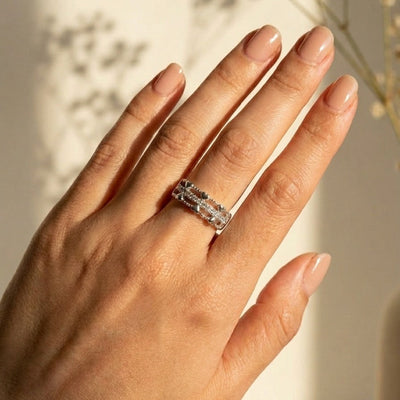 Hand wearing a silver ring with a blurred background