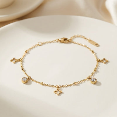 Gold bracelet with star and heart charms on a light background