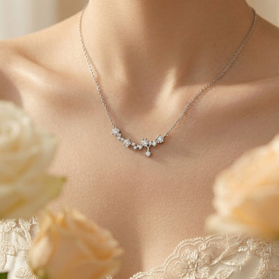 Delicate silver necklace on a person with floral background