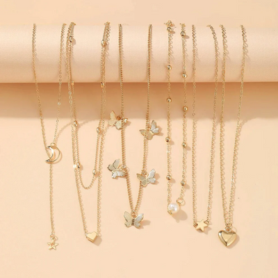 Set of gold necklaces with various charms on a beige background