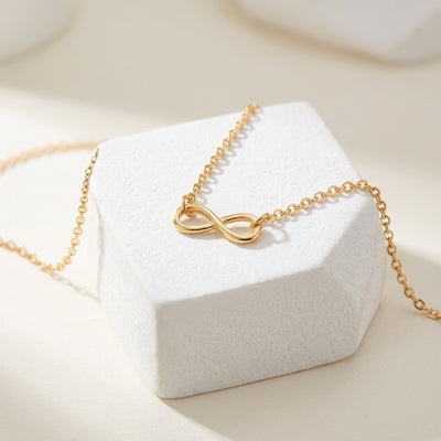 Gold infinity necklace on a white jewelry box