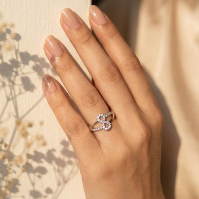 Hand wearing a diamond ring with a blurred natural background
