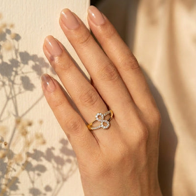 Hand wearing a diamond ring with a blurred natural background