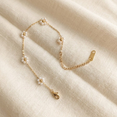 Gold bracelet with pearls on a beige fabric background