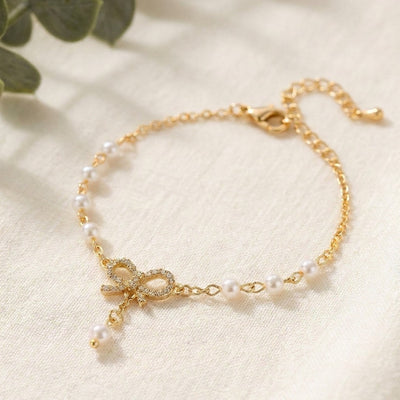 Gold bracelet with pearl accents on a light background