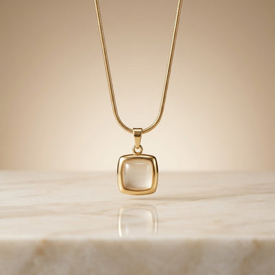 Gold necklace with a square pendant on a beige background