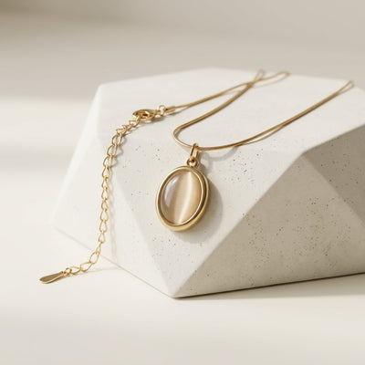 Gold necklace with a pendant on a white geometric block