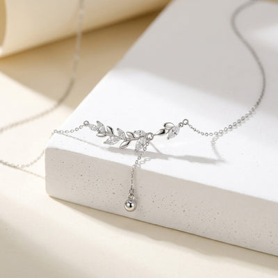 Silver necklace with leaf design on a white surface